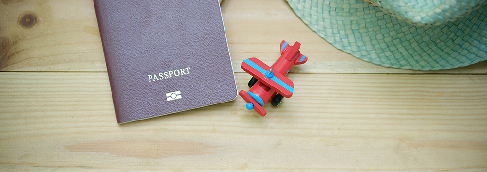 An overhead shot of a passport and toy plane.